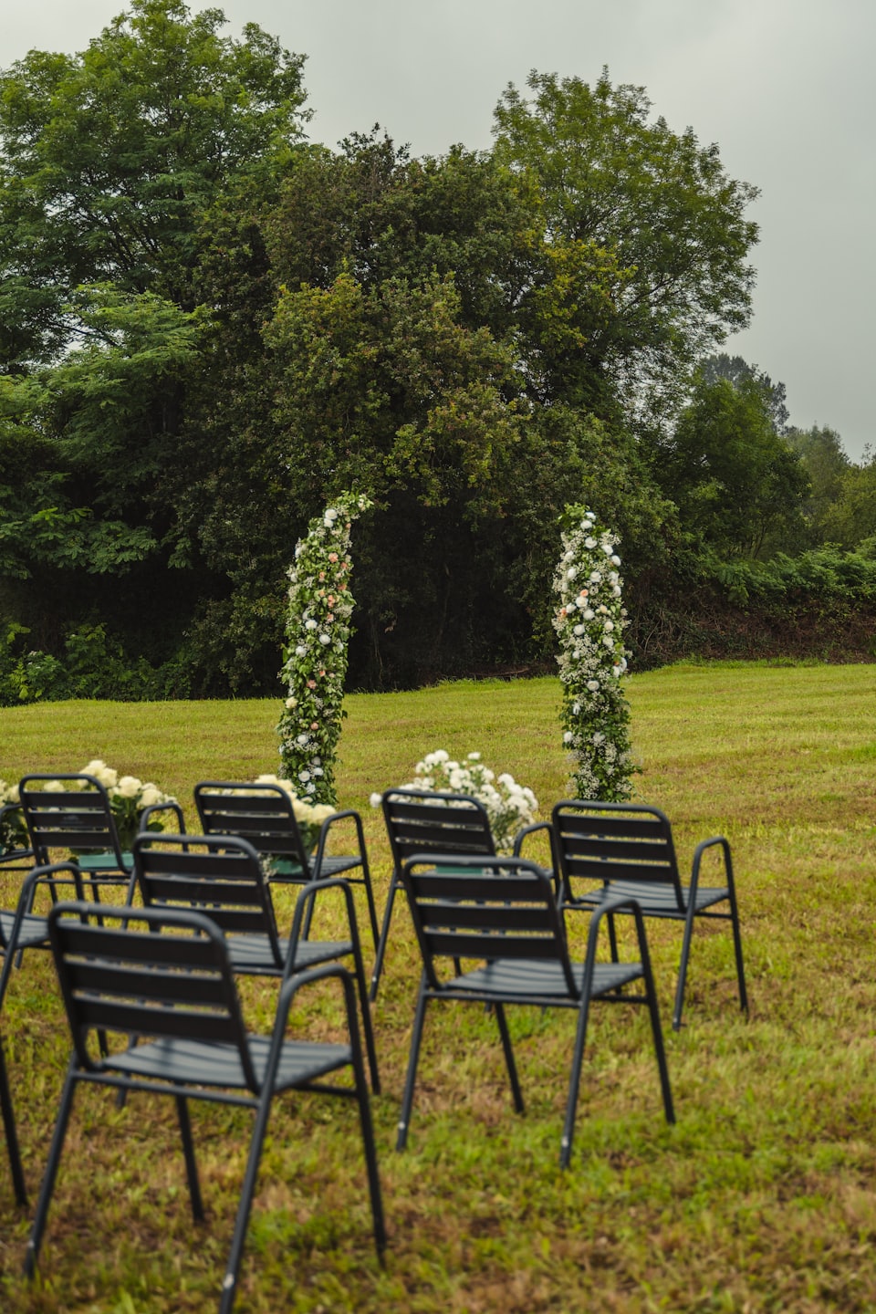 Two floral arches on a green lawn for an outdoor ceremony.