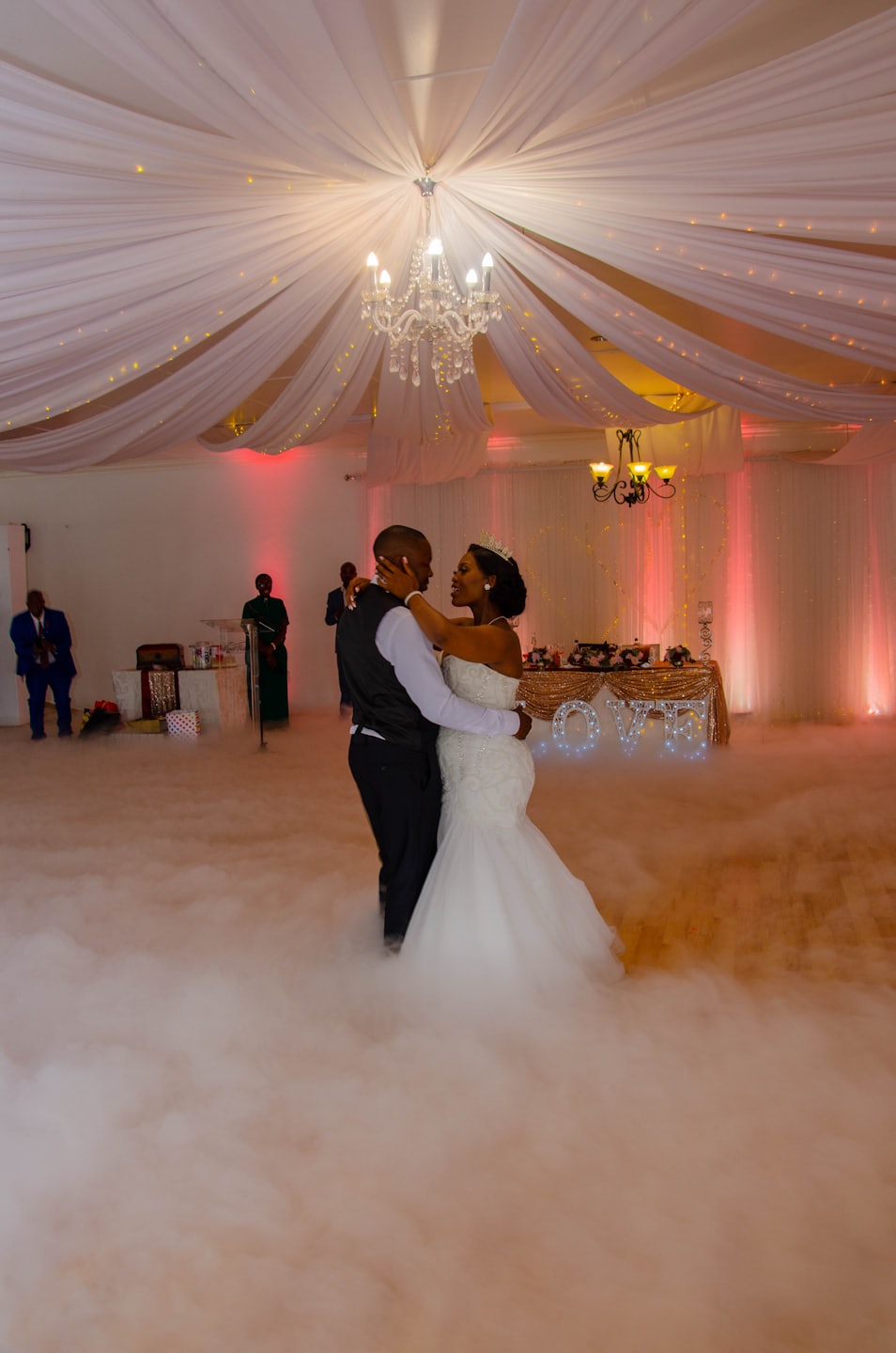 Newlyweds dance their first dance amid wedding reception fog.