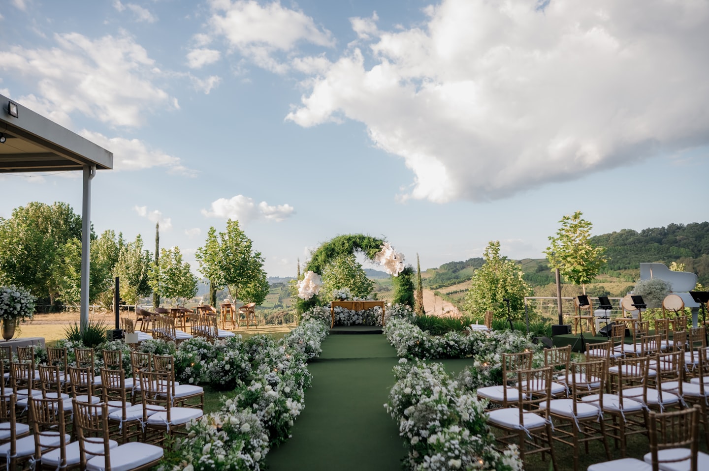 Outdoor wedding ceremony with gold chairs and floral arrangements.