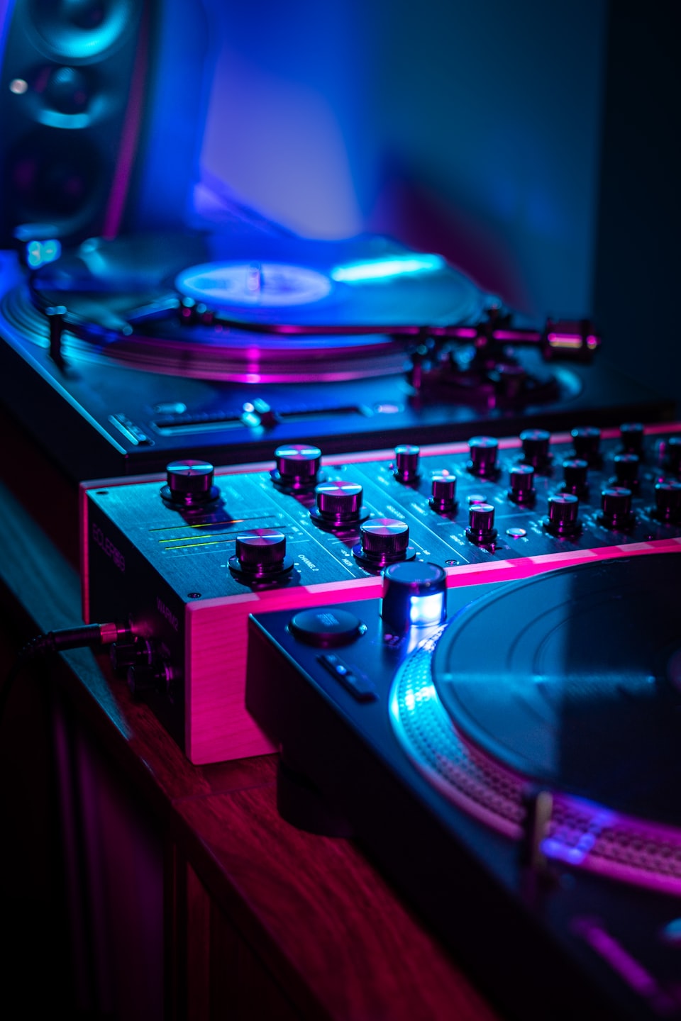 Professional DJ turntables and a mixing console on a table.