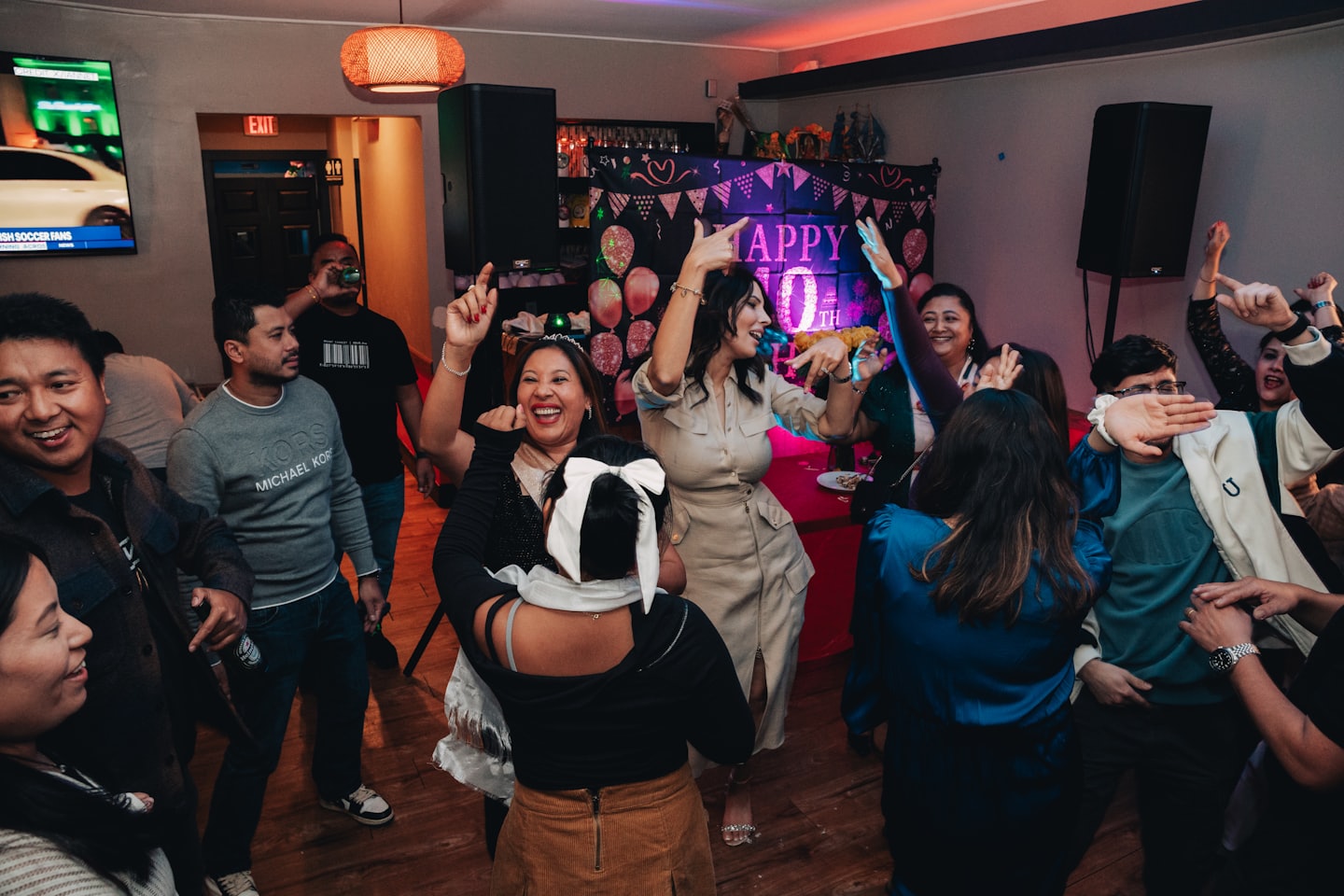Diverse adults happily dancing and celebrating at an indoor event.